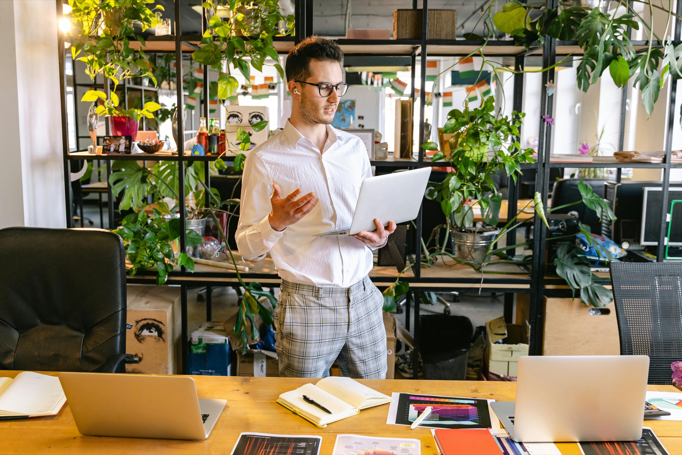 A professional standing in an office with a laptop during a work presentation.