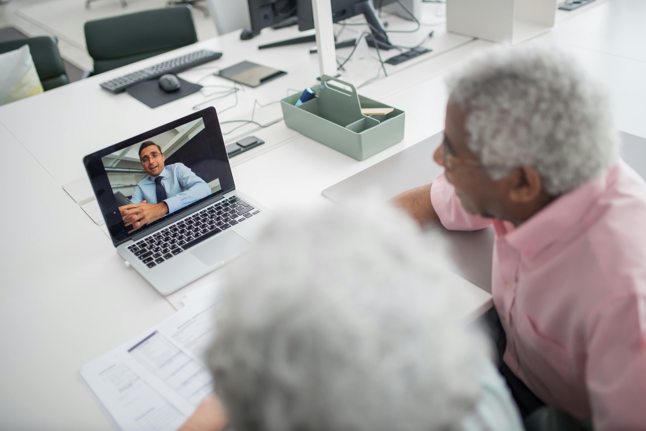 People gathered around a laptop during a professional video call in an office.